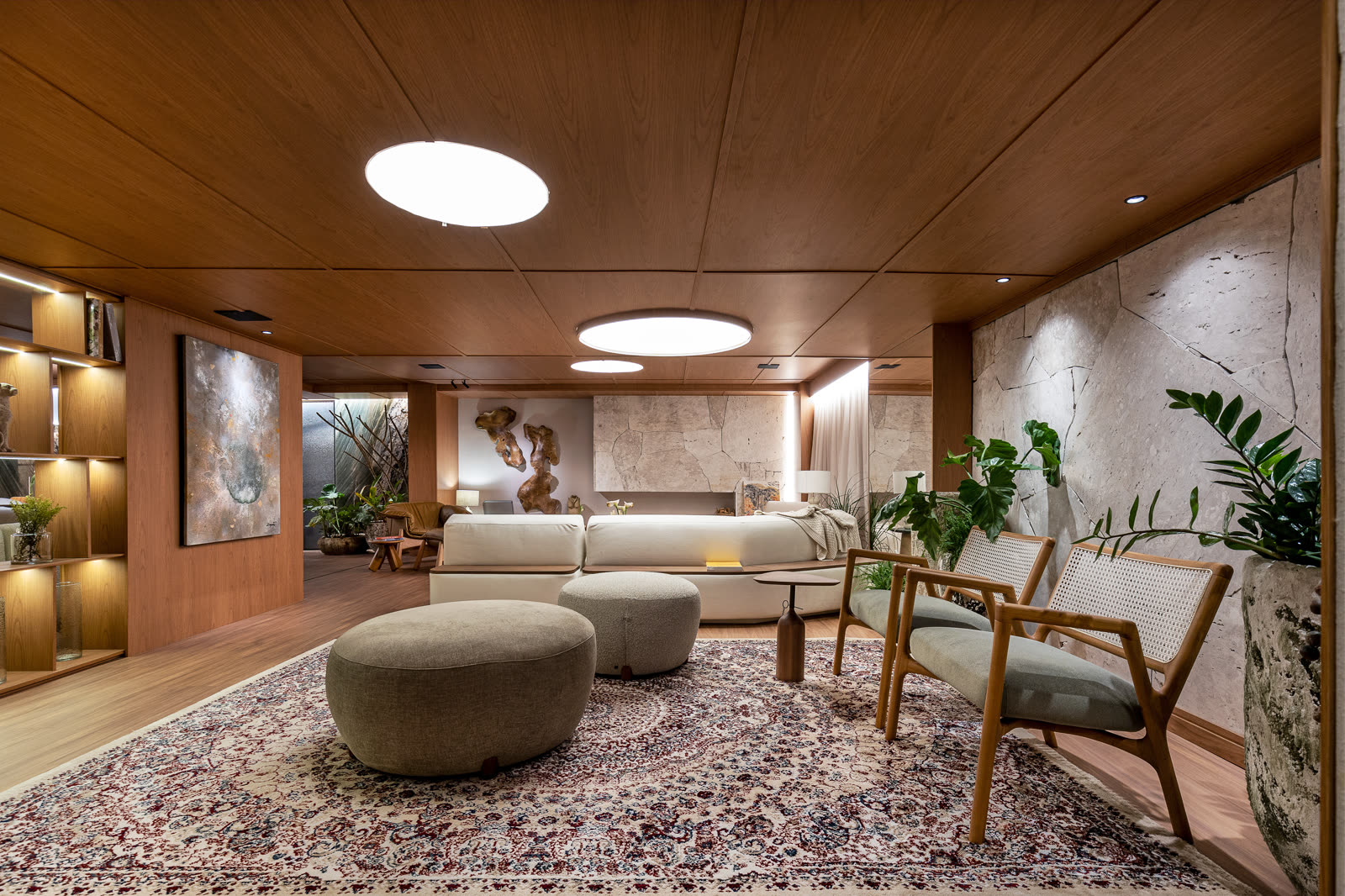 Visão geral do living com claraboia oval, tapete persa e poltronas em madeira