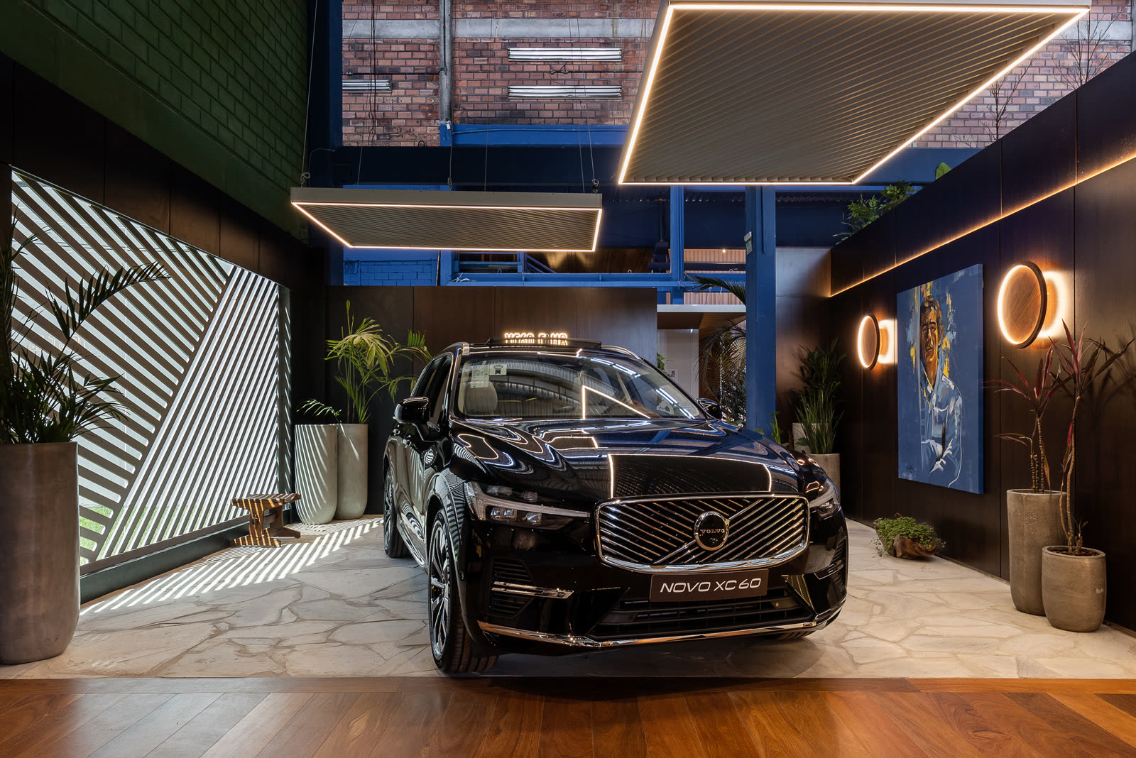 Volvo preto na garagem gourmet Raízes e Rodas, com painel ripado e iluminação em moldura no teto