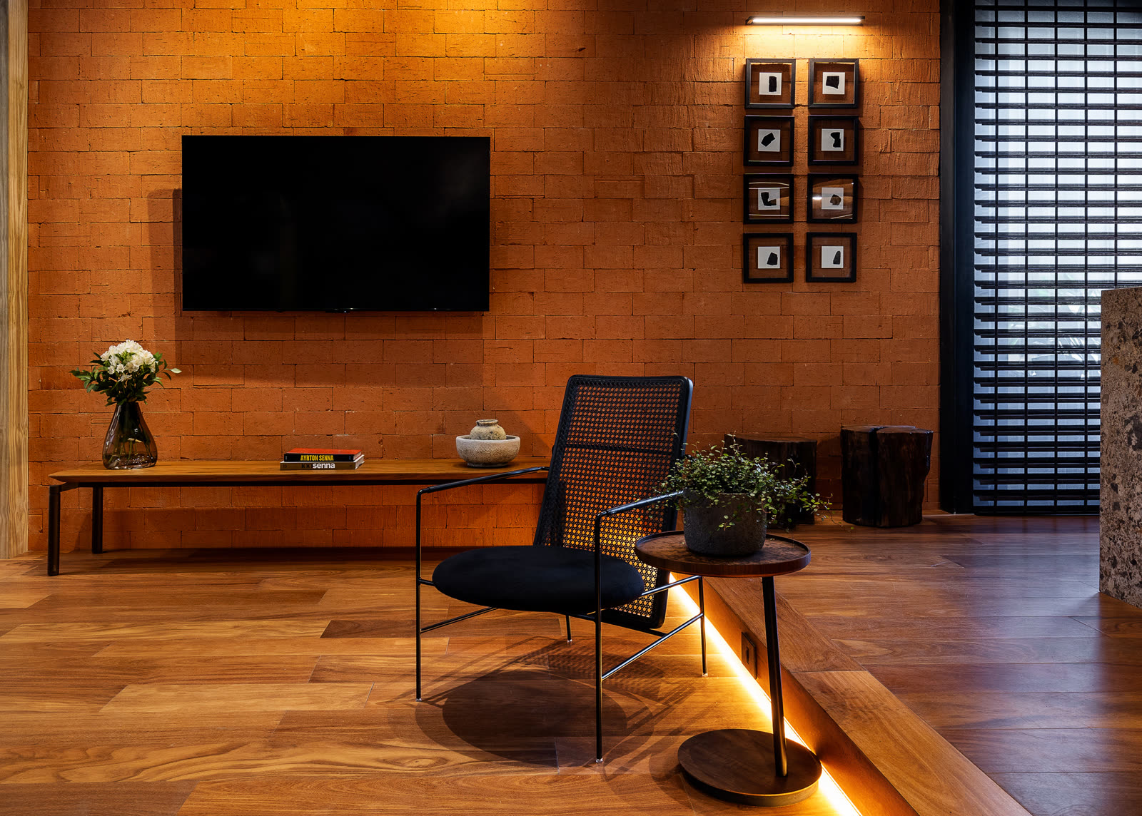 Parede em terracota com TV e poltrona de palhinha preta